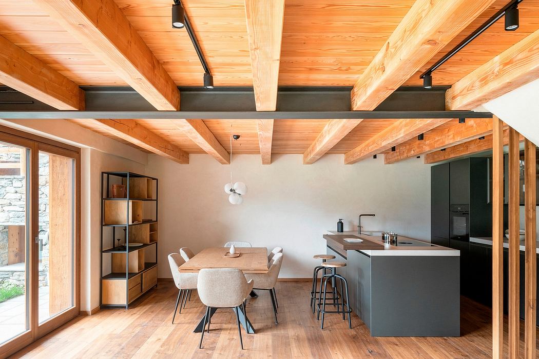 A cozy, modern open-plan living area with wooden beams, gray cabinetry, and a dining table.