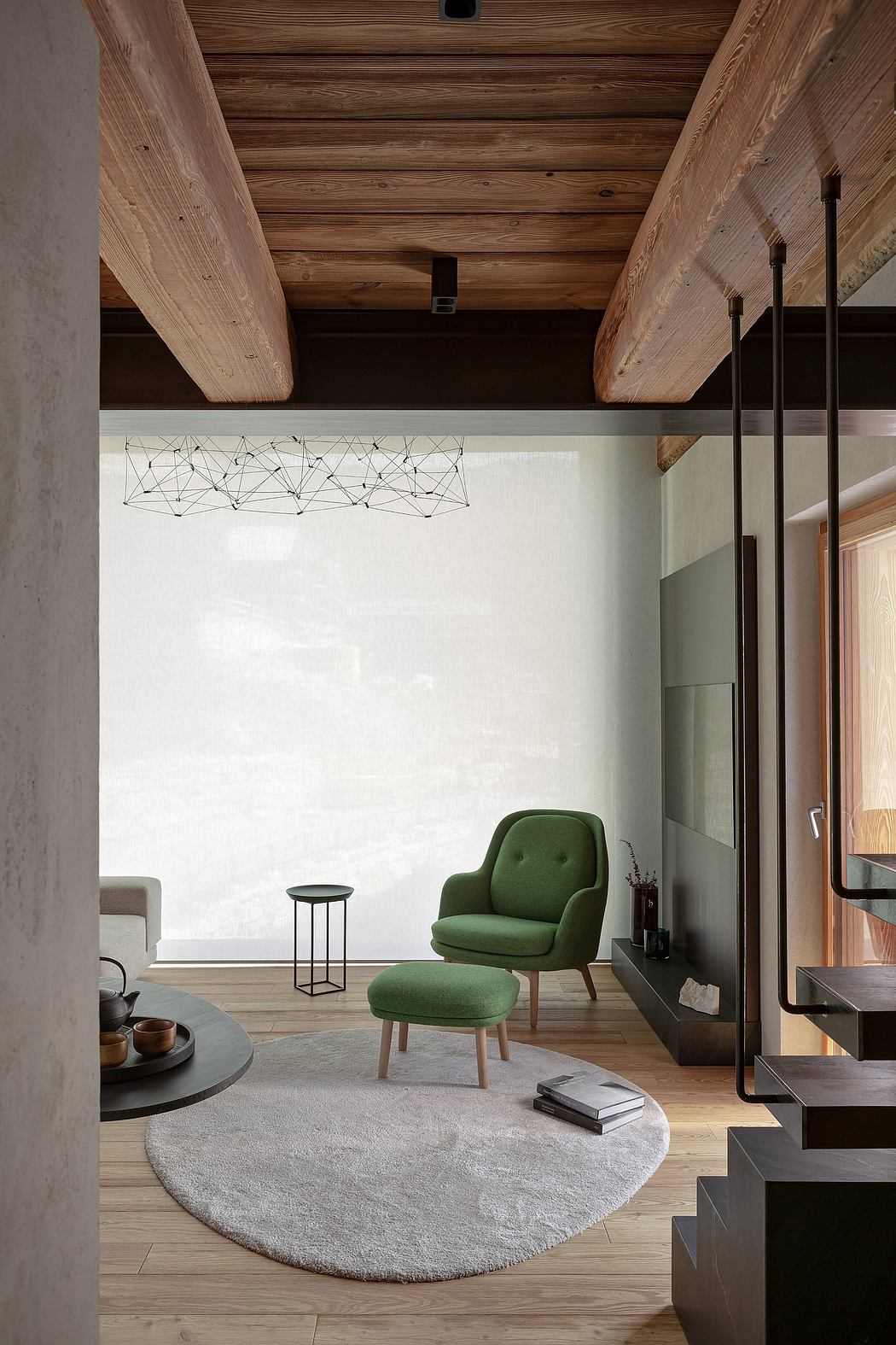Modern living room with exposed beams, green chair, and geometric light fixture.