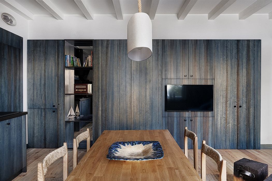 Modern dining room with blue textured walls, wooden table, and pendant light.