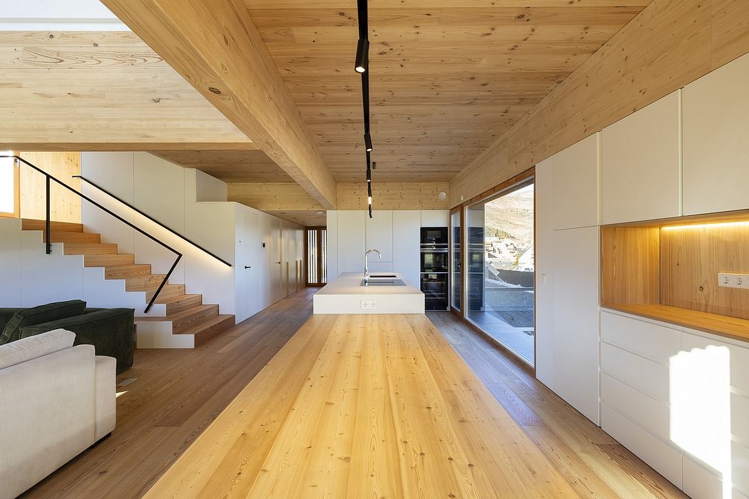 Warm, modern interior with timber ceiling, sleek kitchen, and open staircase.