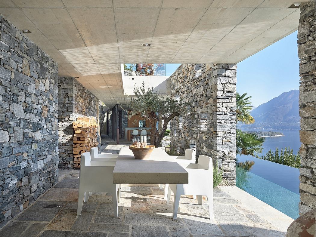 Outdoor dining area with stone walls, white table, and sea view.
