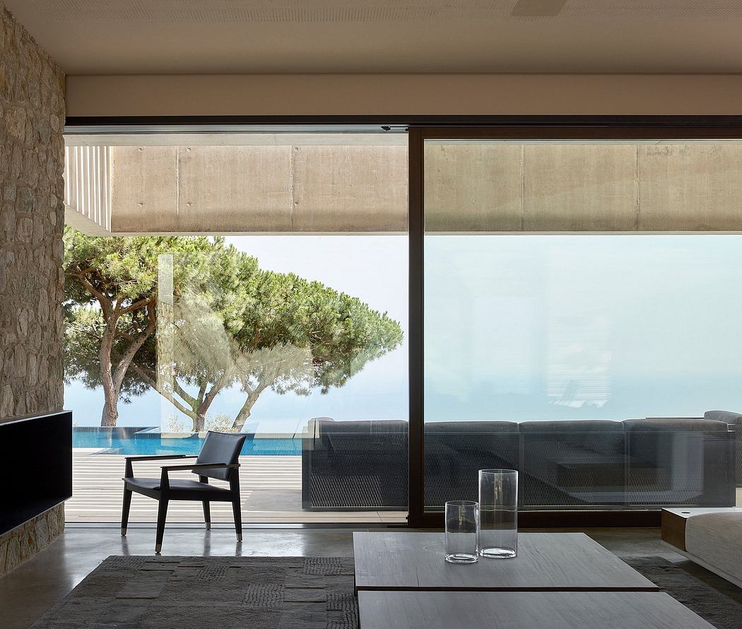 Modern room interior with glass wall overlooking trees and the ocean.