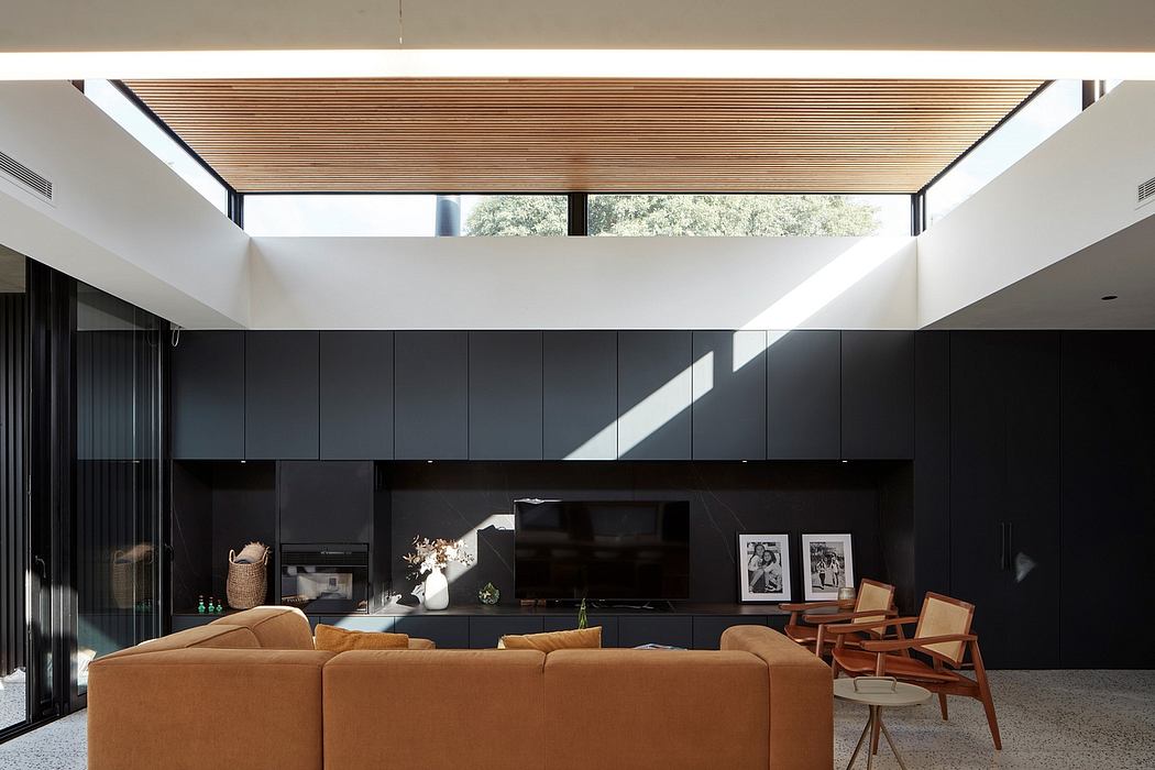 Modern living room with a skylight, black walls, tan sofa, and