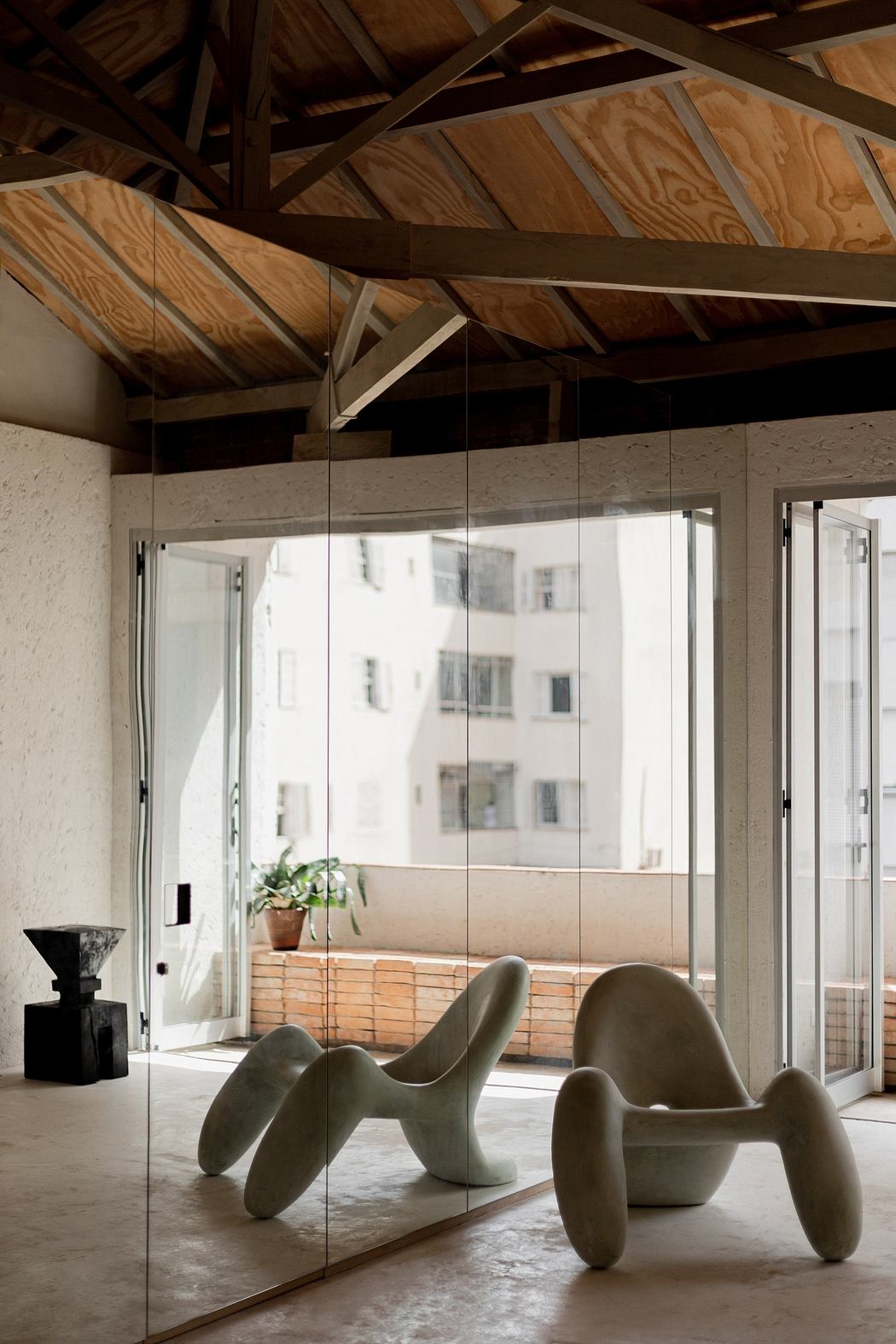 Contemporary space with exposed wooden beams, glass partitions, and unique chairs.