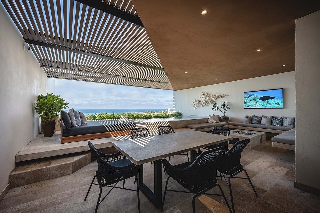 Modern patio with dining table, slatted roof, and ocean view.