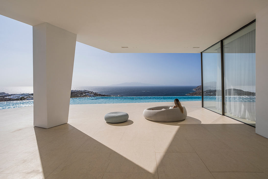Modern minimalist interior with ocean view, large window, and seating.