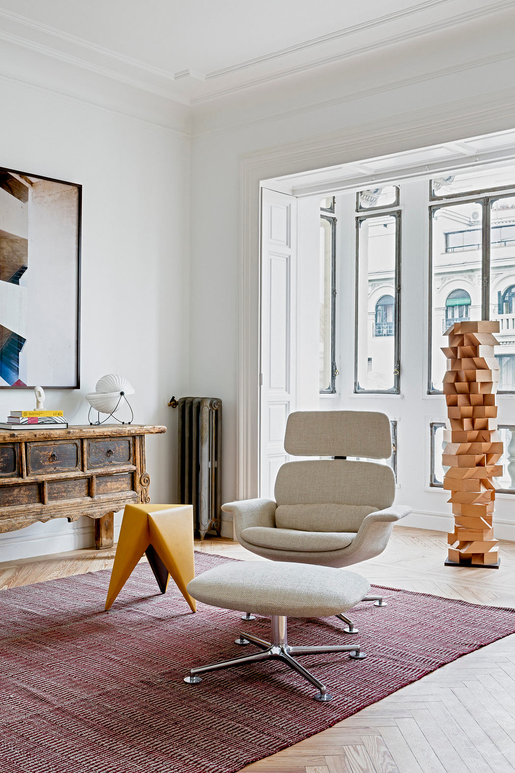 Contemporary living room with eclectic furnishings and tall windows.