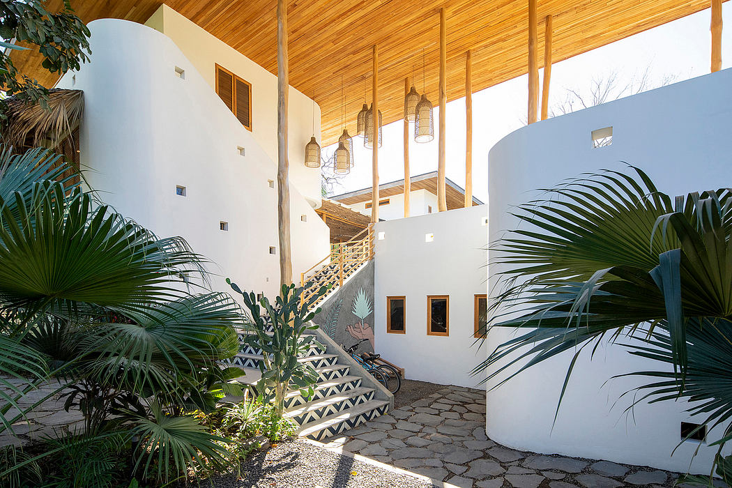 Courtyard with tropical plants, white curved walls, and wooden beams.