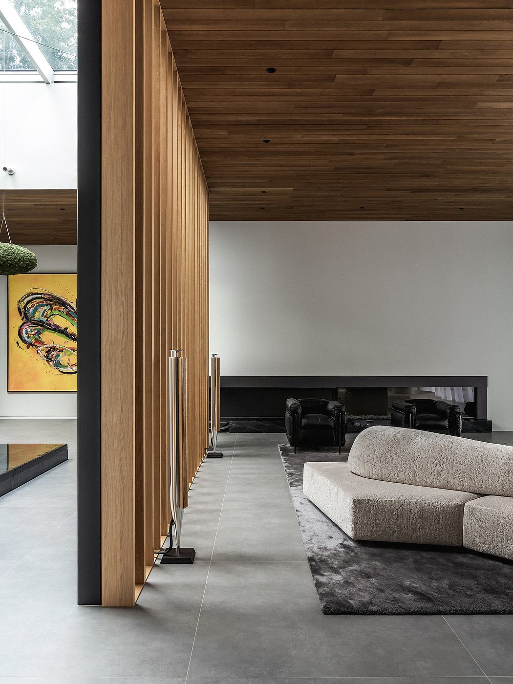 Minimalist living room with wood-paneled walls, concrete floor, and plush furniture.