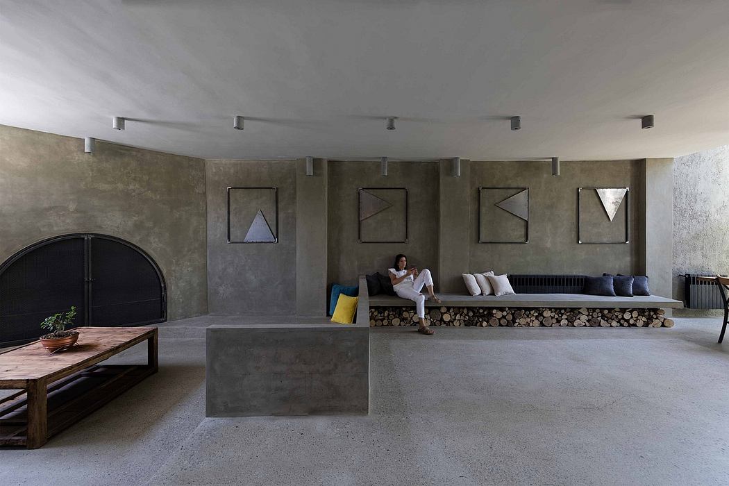 Minimalist living room with concrete walls, bench seating, and a person relaxing.