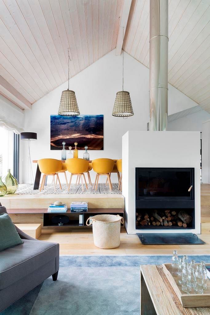 Modern living room with vaulted ceiling, fireplace, and yellow bar stools.