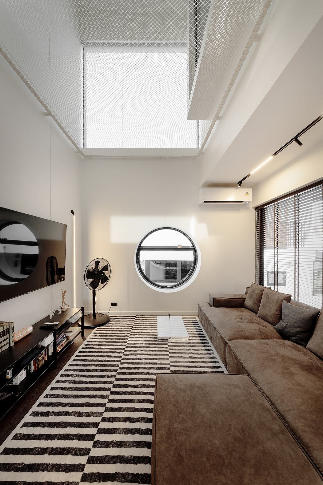 Contemporary living room with high ceiling and circular window.