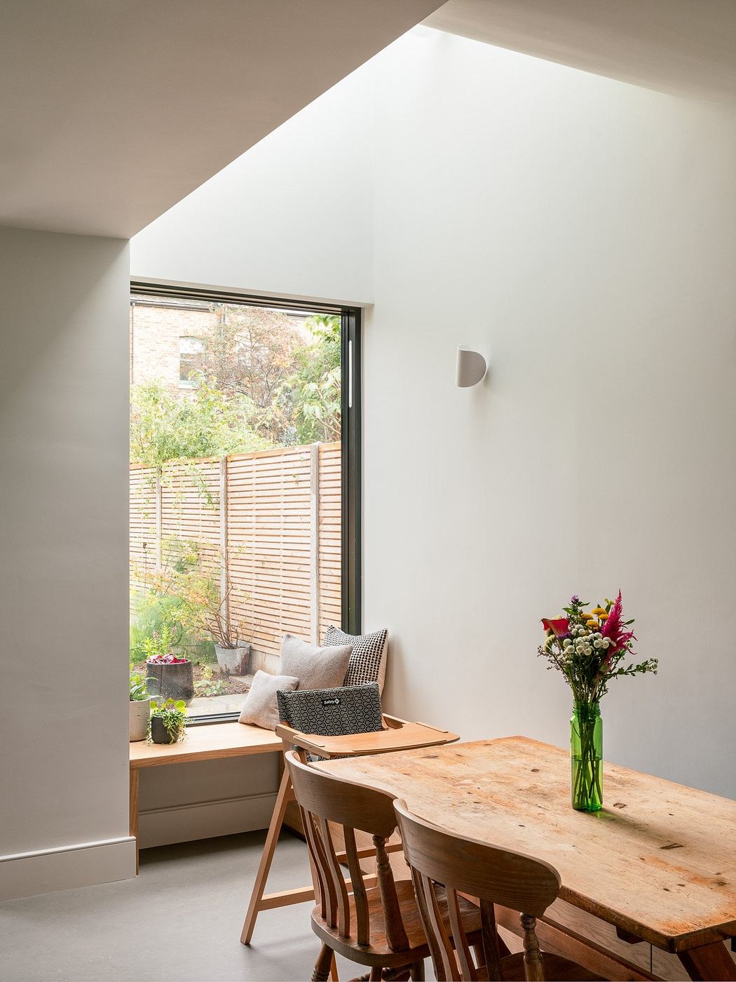 Minimalist dining corner with large window and wooden table.