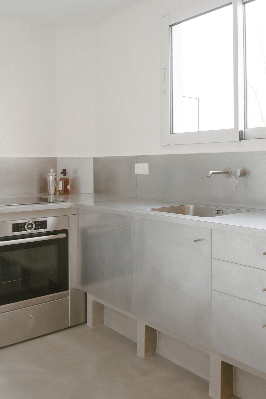 Minimalist kitchen with stainless steel countertops and white walls.