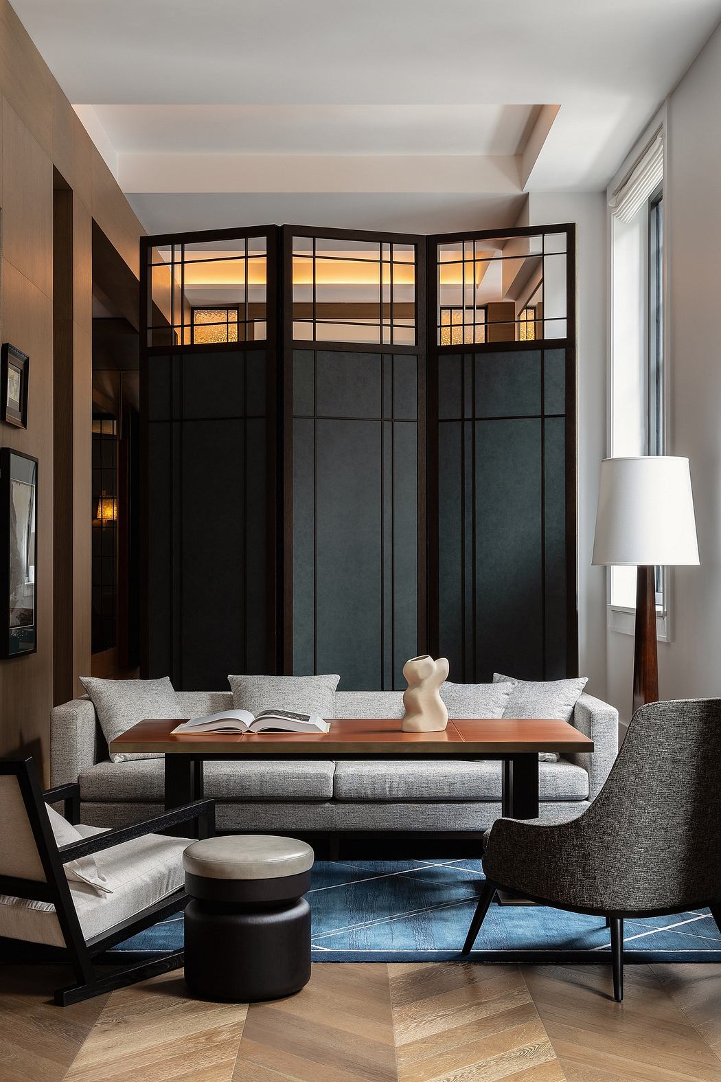 Elegant living room with black room divider, grey sofa, and floor lamp.