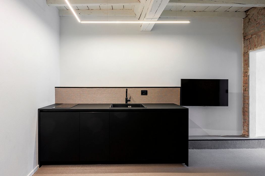 Sleek, minimal kitchen with black cabinets and wooden backsplash in modern industrial space.