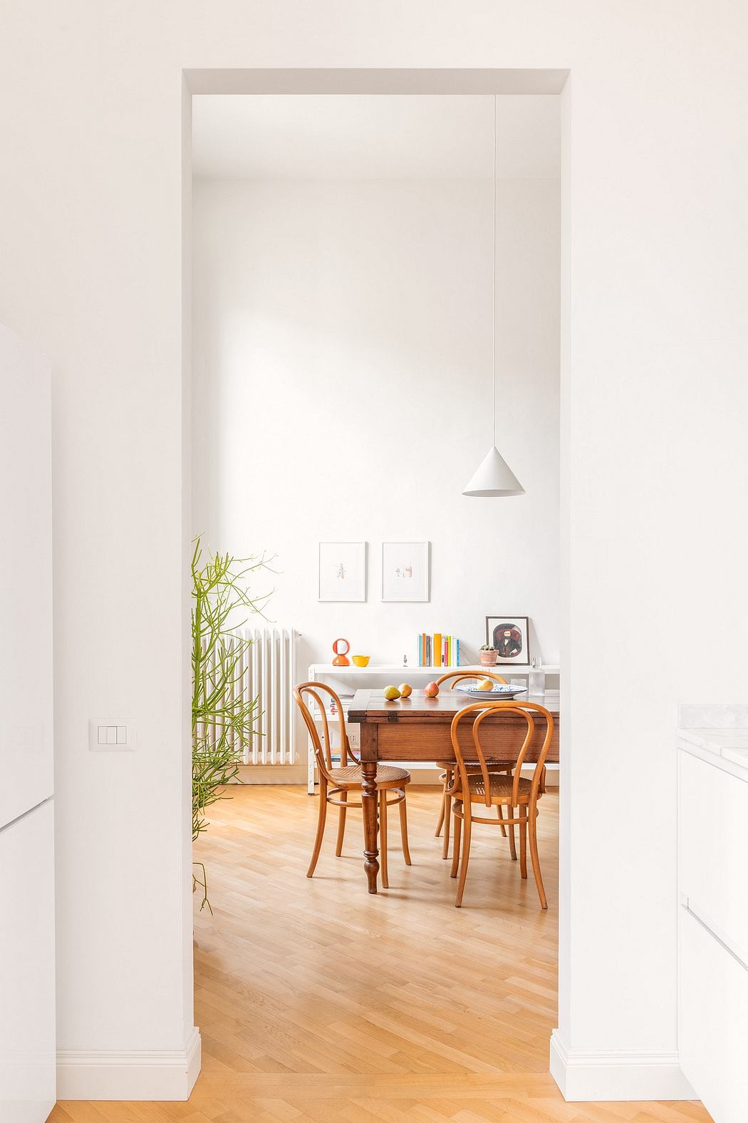 View through a doorway of a bright dining room with a wooden table and chairs.
