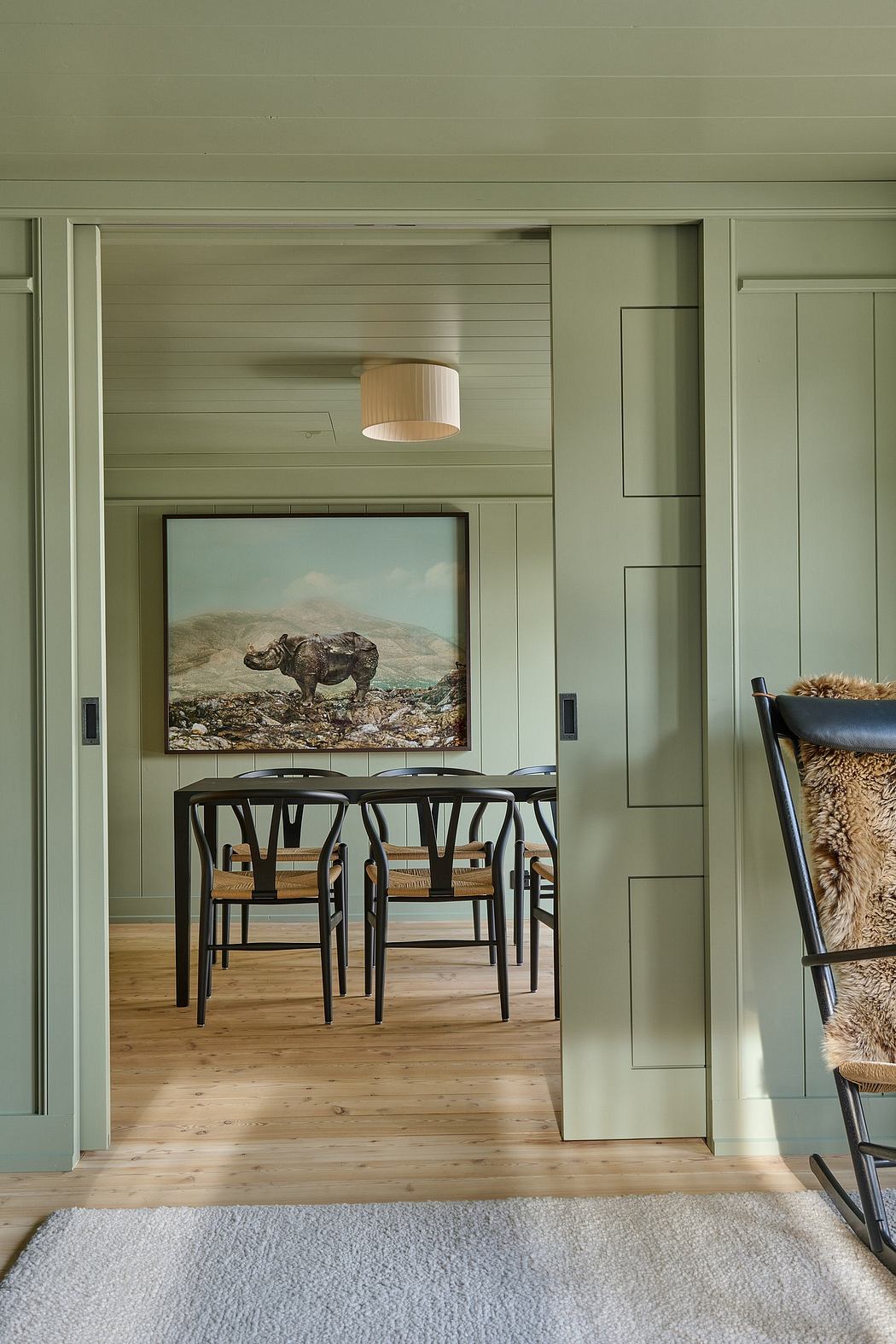 Dining room with green walls, black chairs, and a picture of an elephant