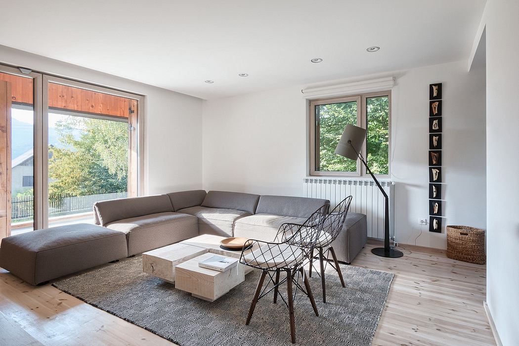 Minimalist living room with large sectional sofa, wire chairs, and wood-paneled walls.
