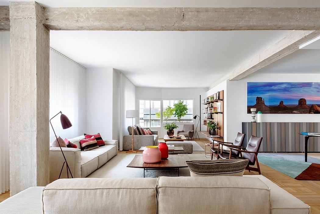 Bright, open-concept living space with exposed concrete beams, modern furniture, and an eye-catching landscape artwork.