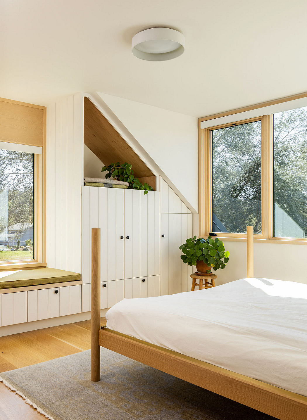 Bright, minimalist bedroom with wooden finishes and large windows.