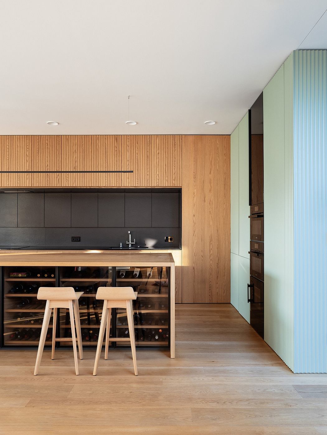 Contemporary kitchen with wood accents and minimalist bar stools.