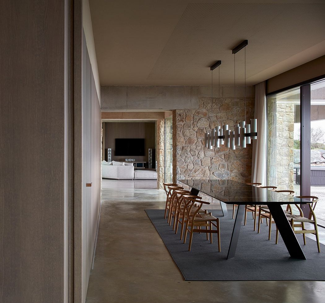 Modern dining room with stone wall, sleek table, and pendant lights.