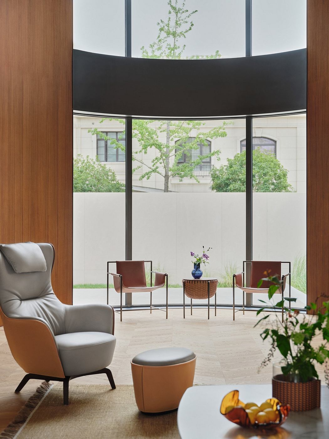 A modern, minimalist interior with curved glass walls, wood accents, and stylish furnishings.
