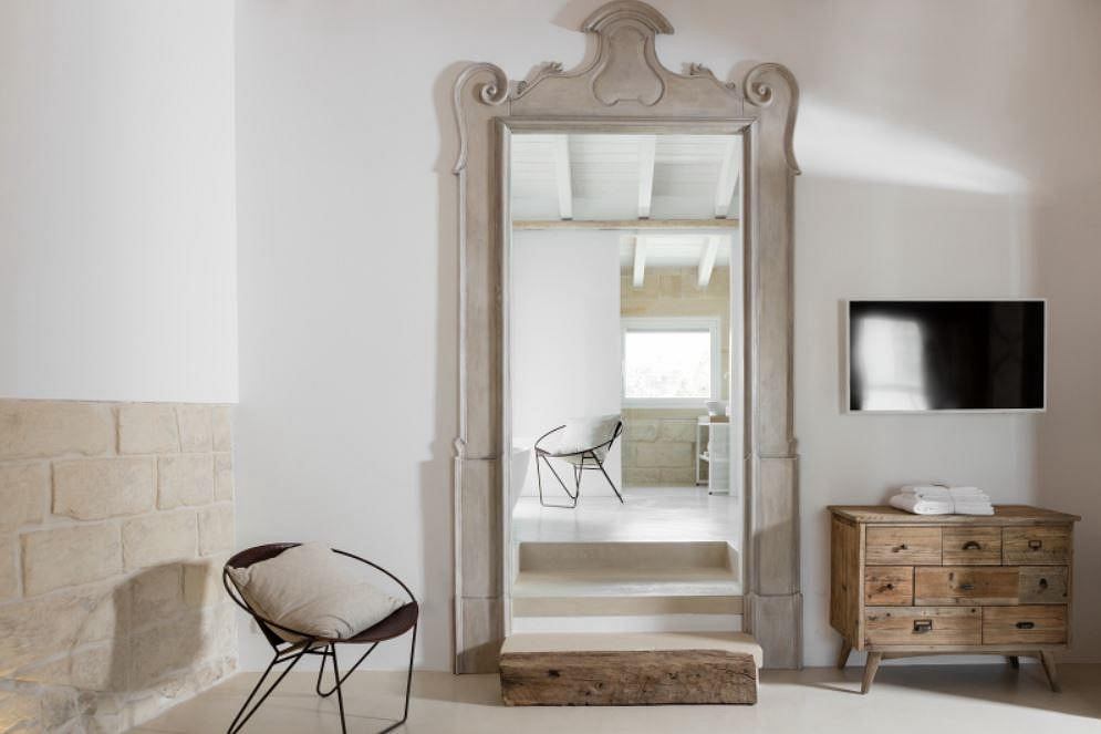 Ornate antique mirror frame, stone fireplace, wooden furniture, and minimalist decor.