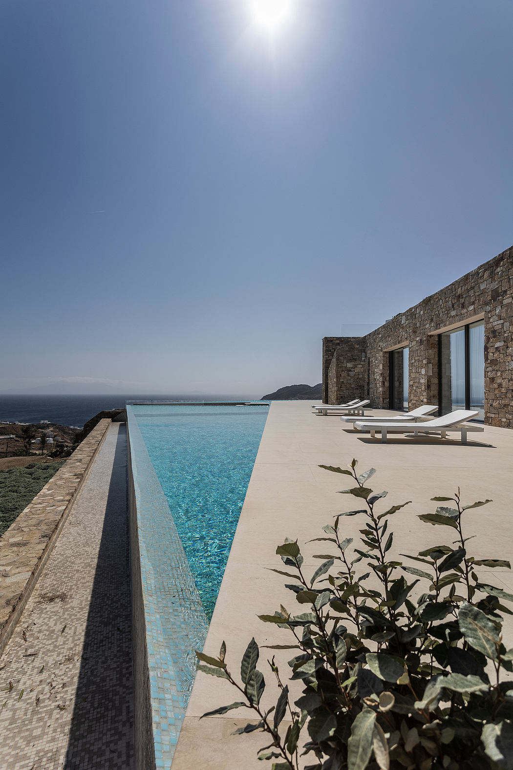 Infinity pool by stone villa overlooking the sea.