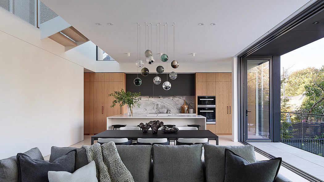 Modern kitchen and dining area with wooden cabinets and pendant lights.