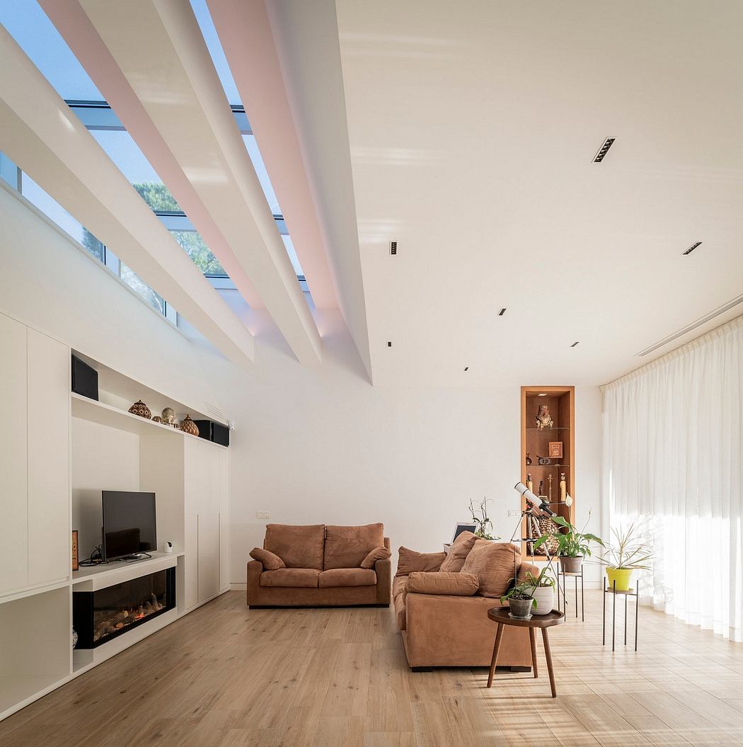 Modern living room with white walls, angled ceiling beams, and tan furniture.