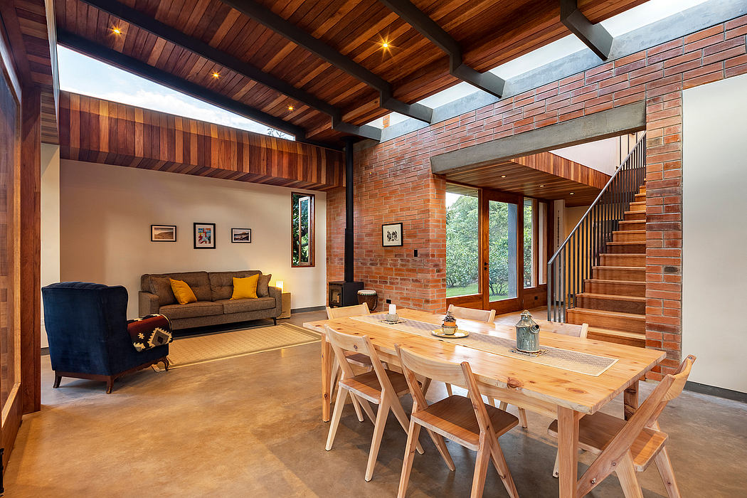 A cozy, rustic open-concept living space with wooden beams, brick walls, and a large dining table.