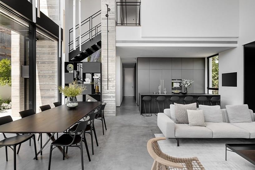 Minimalist open-plan living space with concrete floors, exposed ceiling beams, and sleek furnishings.