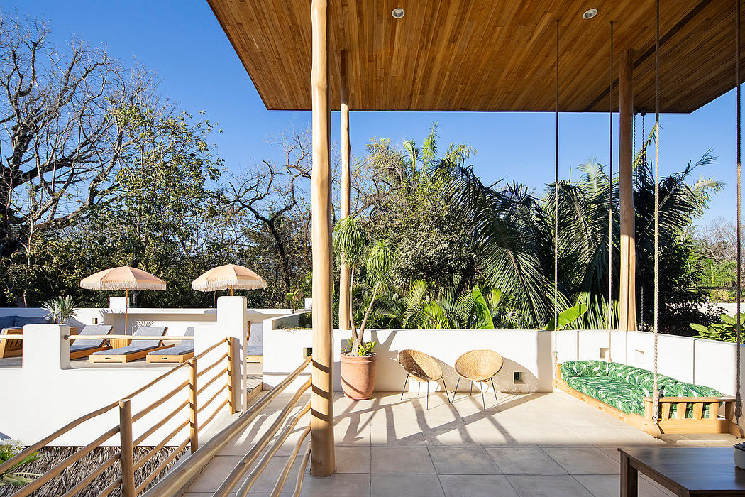 Modern outdoor terrace with wooden ceiling and furnishings overlooking greenery.