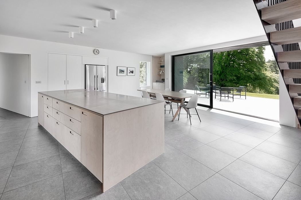 Sleek, minimalist kitchen with large island, floor-to-ceiling windows, and modern decor.