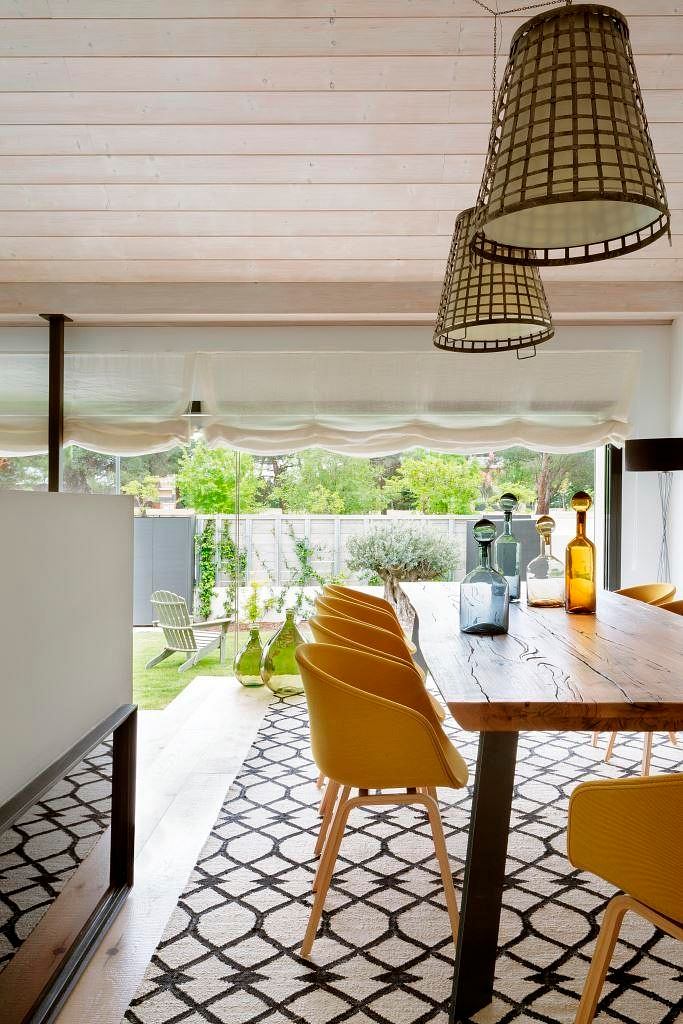 Bright dining space with wicker lamps, a wooden table, yellow chairs, and