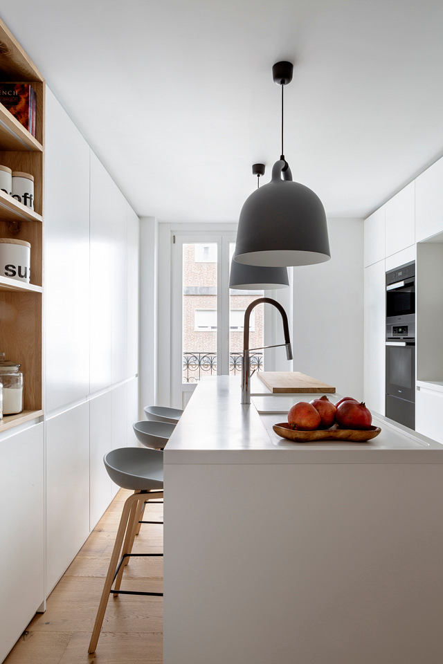Sleek white kitchen with pendant lighting over a breakfast bar.