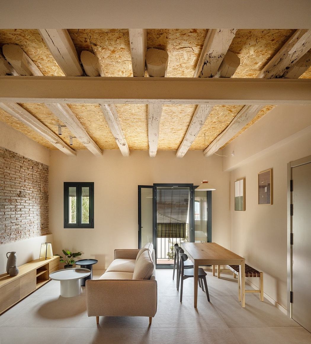 Cozy open-concept living space with exposed wooden beams and brick walls, modern furnishings.