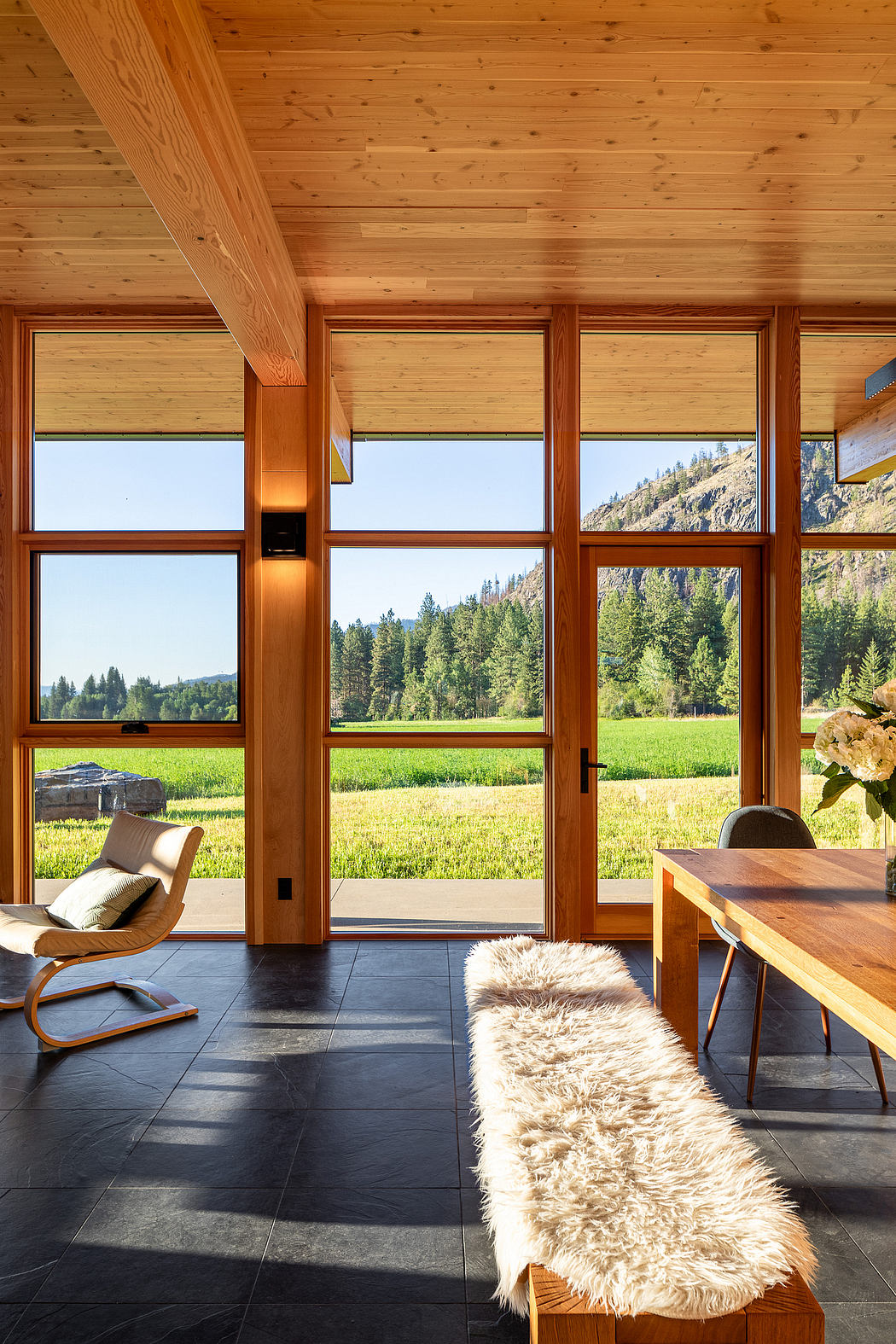 A cozy wooden cabin with large windows overlooking a scenic mountain landscape.