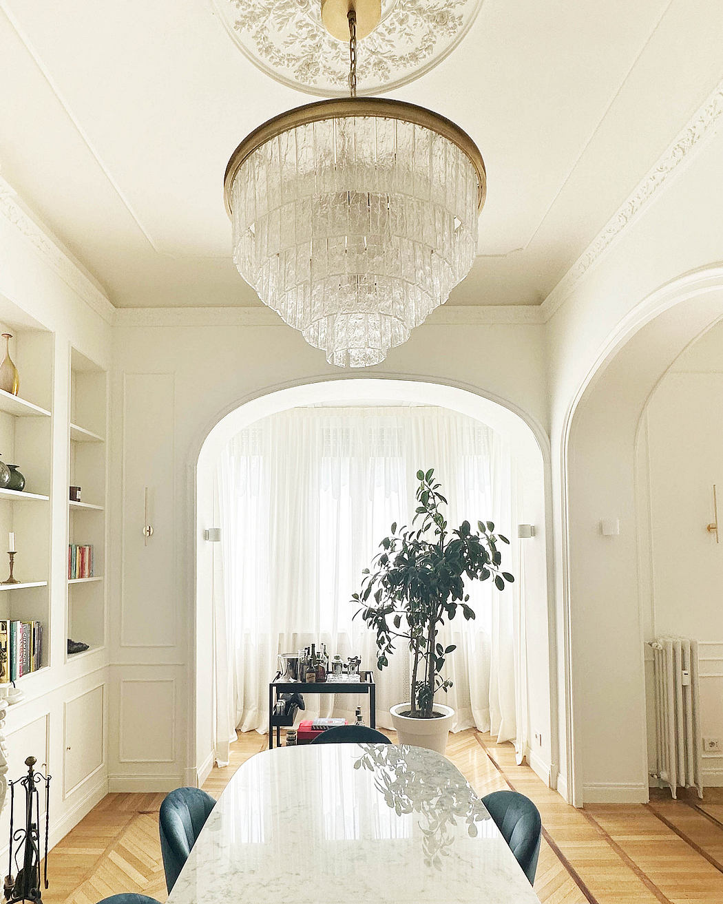 Elegant dining room with crystal chandelier, arched doorways, and built