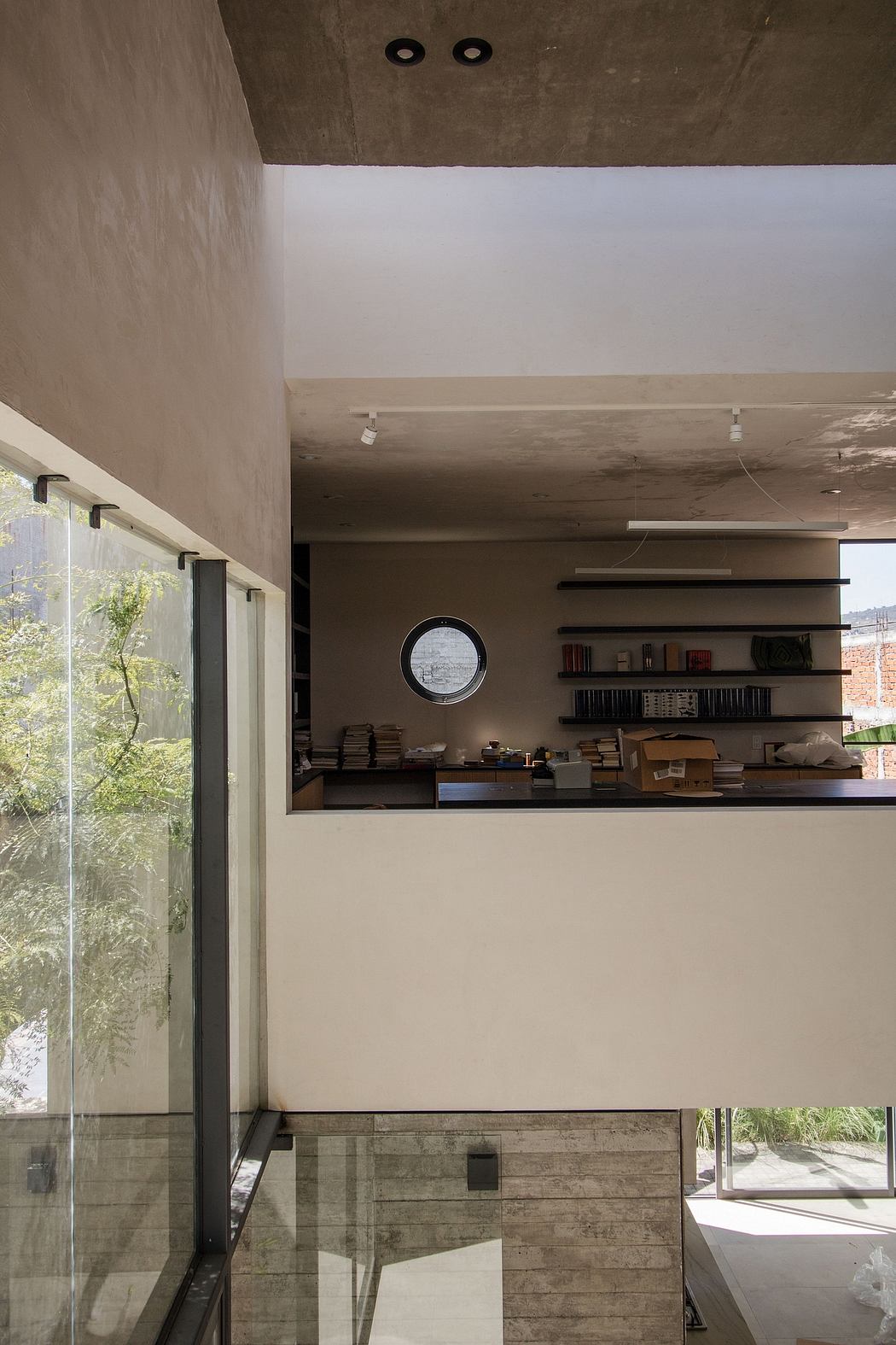 Modern interior with exposed concrete ceiling and minimalist shelf by glass wall.