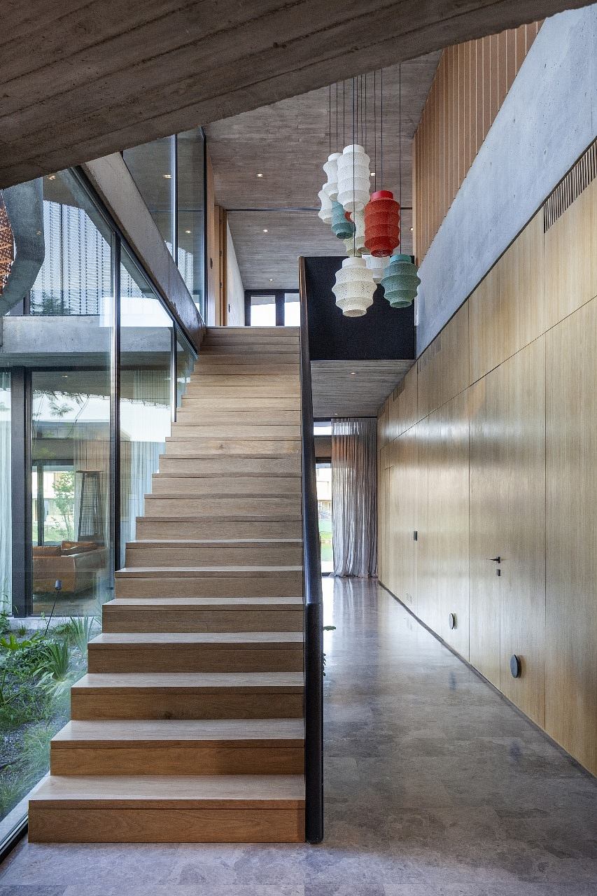 Modern staircase with wooden steps, hanging lamps, and glass balustrade.