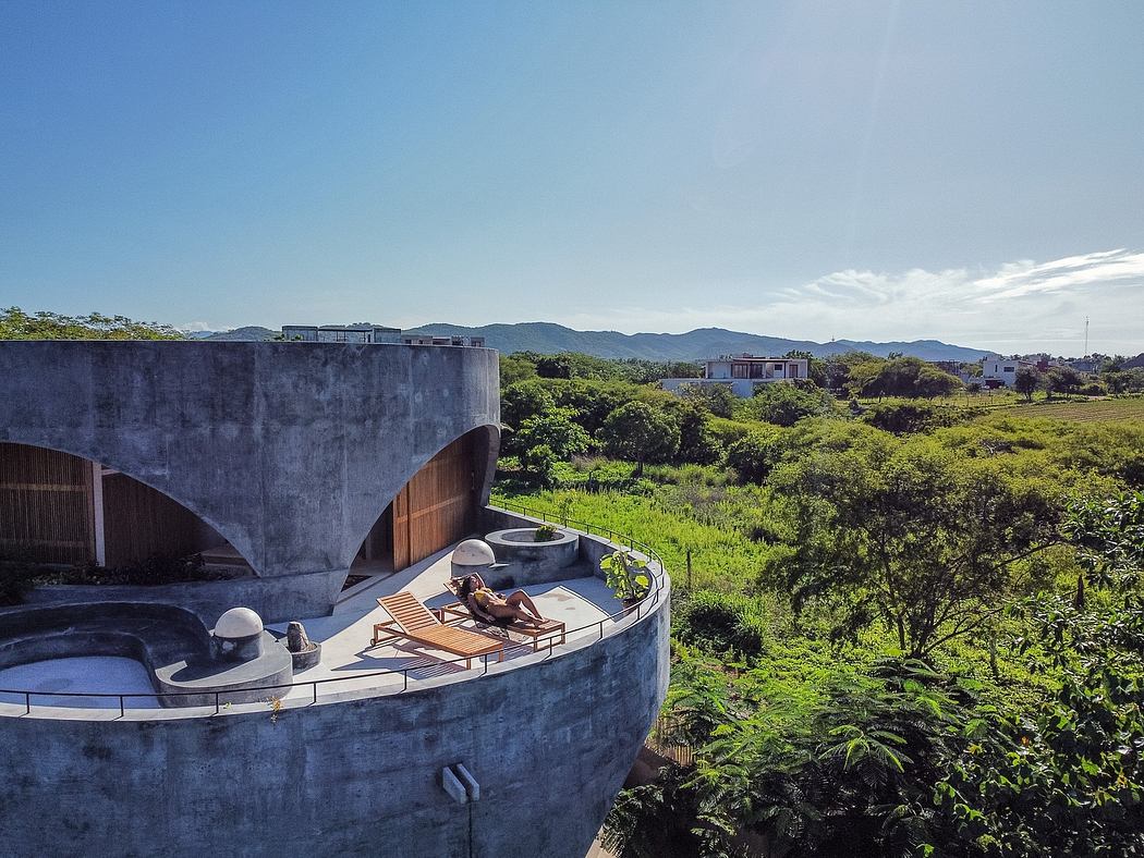 Dramatic concrete architecture with curved balconies nestled in lush green surroundings.