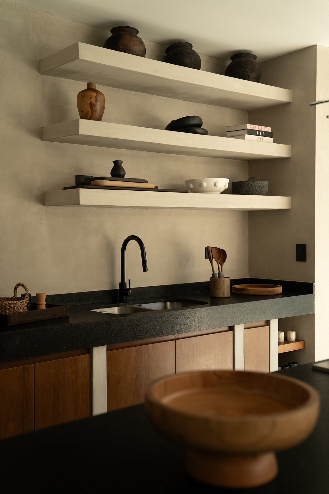 Modern kitchen corner with floating shelves and black countertops.