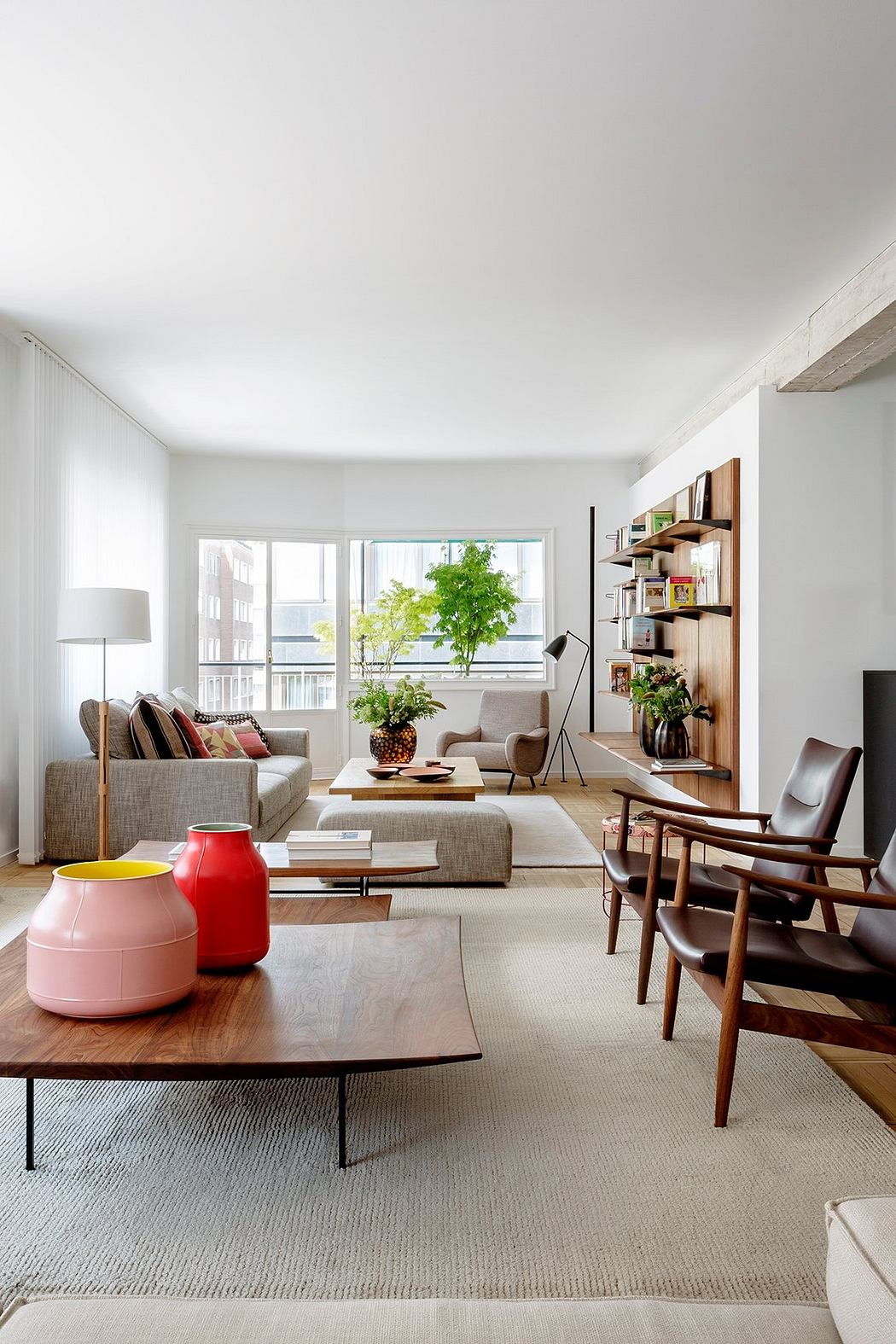 Modern, minimalist living room with neutral furnishings, vibrant accents, and wooden shelving.