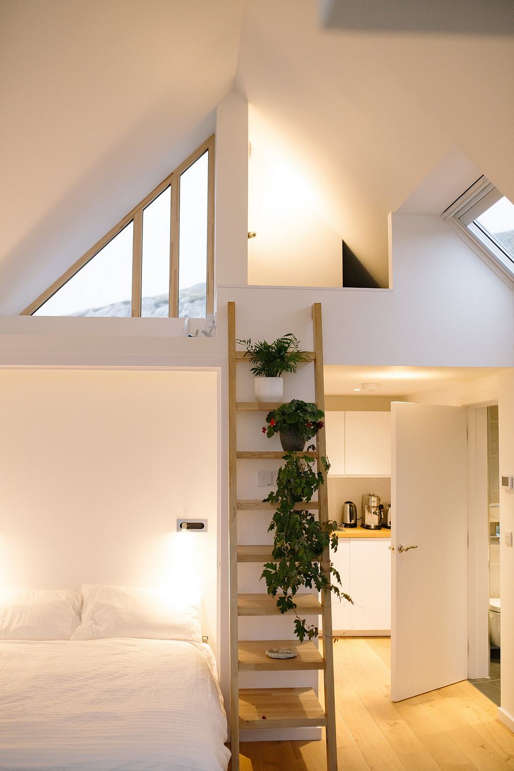Cozy attic bedroom with skylights and a wooden ladder.