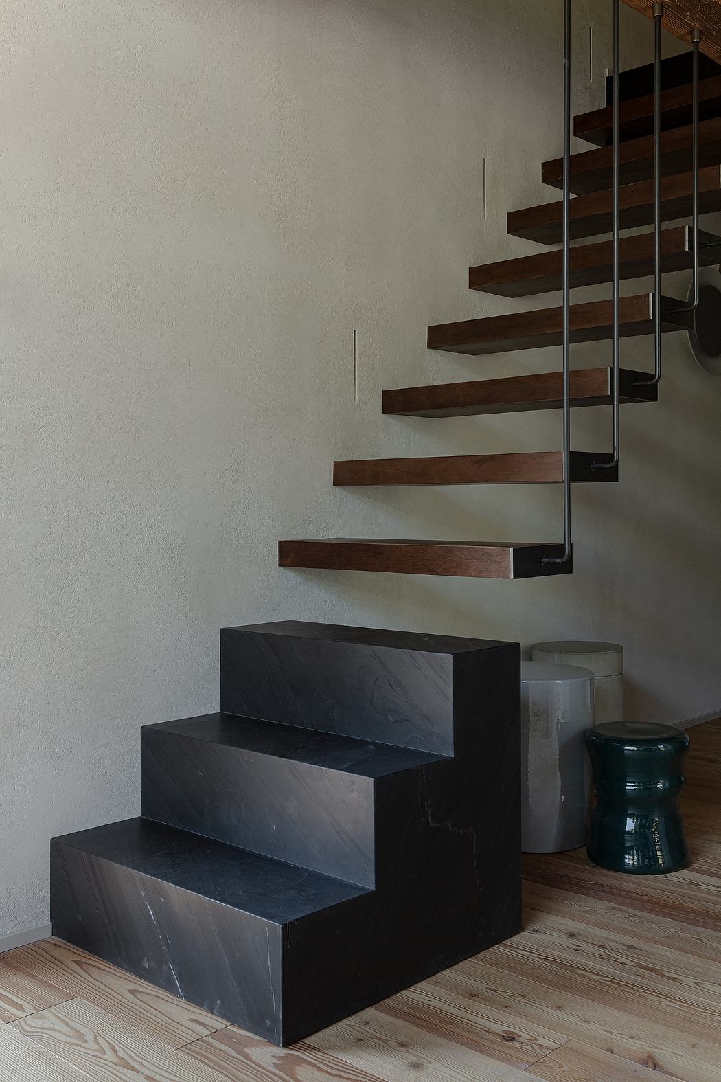 Floating wooden steps on a minimalist staircase with a textured wall.