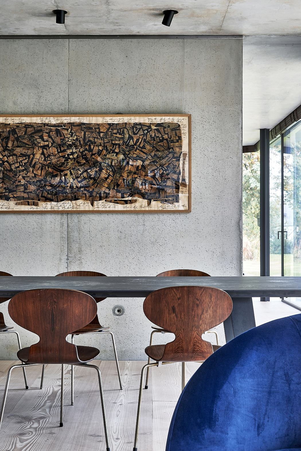 Contemporary dining space with concrete walls and wooden art piece.