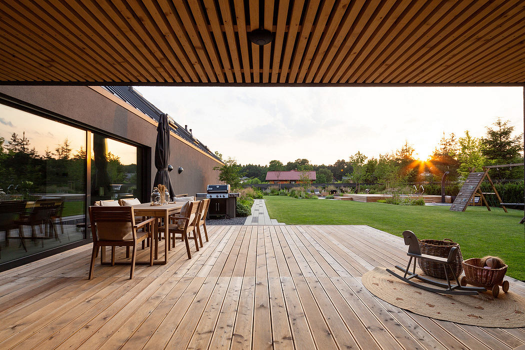 Wooden deck patio with dining set and lawn view at sunset.